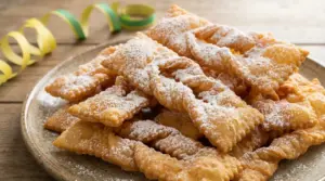 Chiacchiere dorate spolverate di zucchero a velo su un piatto di ceramica