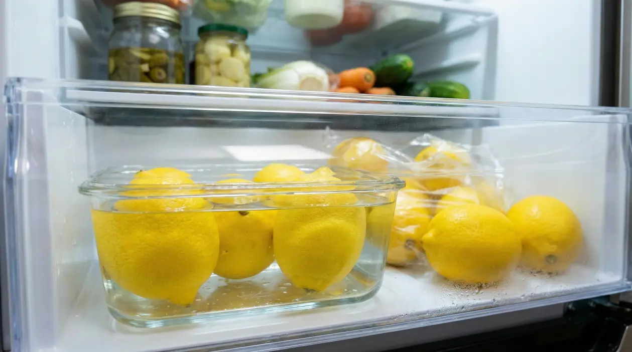 Limoni conservati in un contenitore di vetro con acqua all'interno di un frigorifero.