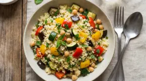 Piatto di cous cous con verdure grigliate e ceci su tovaglietta chiara