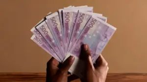 Una persona tiene in mano diverse banconote da 500 euro su sfondo neutro