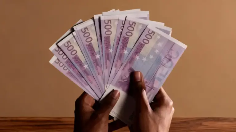 Una persona tiene in mano diverse banconote da 500 euro su sfondo neutro