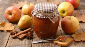 Vasetto di marmellata autunnale con mele, pere e spezie su tavolo rustico