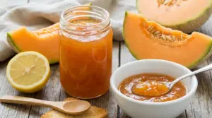 Vasetto e ciotola di marmellata di melone con spicchi di melone e mezzo limone su tavolo di legno