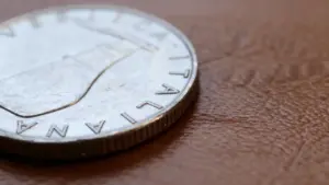 Dettaglio ravvicinato di una moneta italiana da 5 lire posata su una superficie marrone