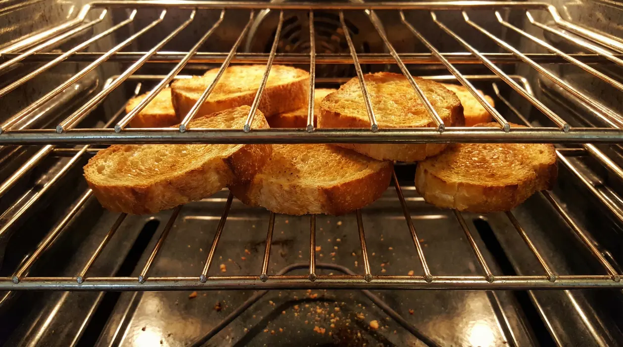 Fette di pane tostato disposte tra le griglie di un forno acceso