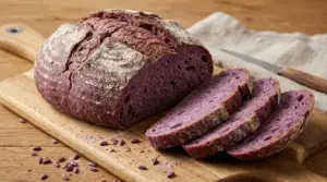 Pagnotta di pane viola tagliata a fette su tagliere di legno