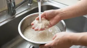 Mani che lavano il riso sotto l'acqua corrente in una ciotola in acciaio
