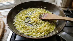 Cipolla tritata che cuoce in olio d'oliva in una padella su fornello