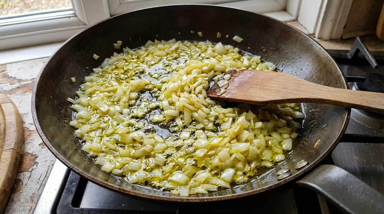 Cipolla tritata che cuoce in olio d'oliva in una padella su fornello