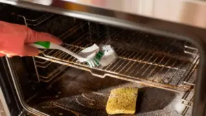 Persona che pulisce un forno incrostato con una spazzola e bicarbonato