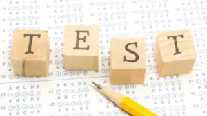 Matita su modulo di test a scelta multipla con blocchi di legno che formano la parola TEST