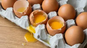 Uova rotte in una confezione di cartone con tuorli che fuoriescono