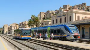 Stazione ferroviaria in Sicilia con treno regionale e autobus SAIS Autolinee.