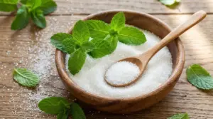 Ciotola di zucchero con foglie di menta fresca e cucchiaio di legno su un tavolo rustico